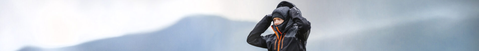 En man håller i sin luva, ett berg i bakgrunden.