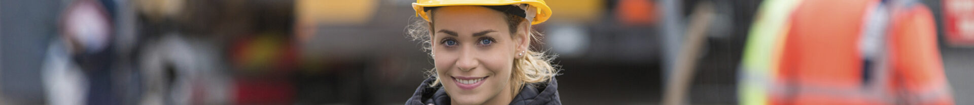 En kvinna i arbetshjälm på en byggarbetsplats.